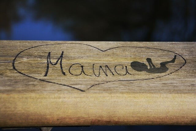 Herz mit Mama-Schriftzug und Baby gezeichnet auf Holz